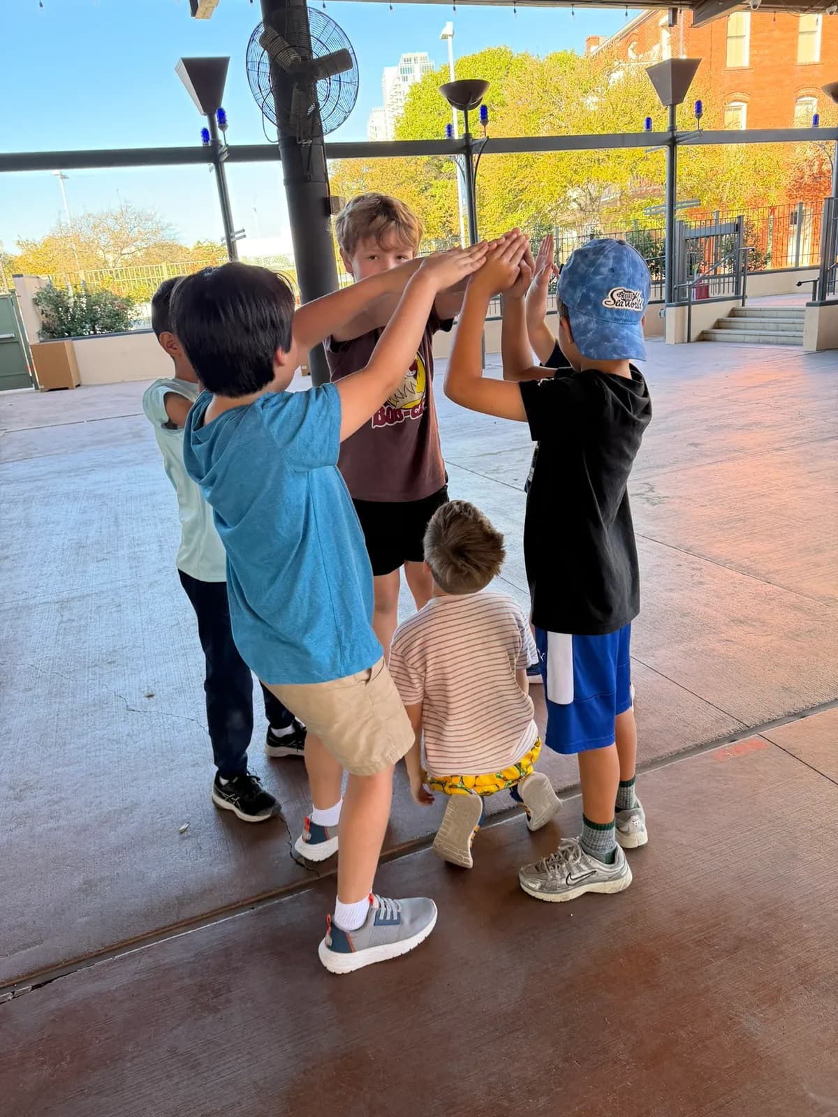Campers putting their hands together at an outdoor pavilion