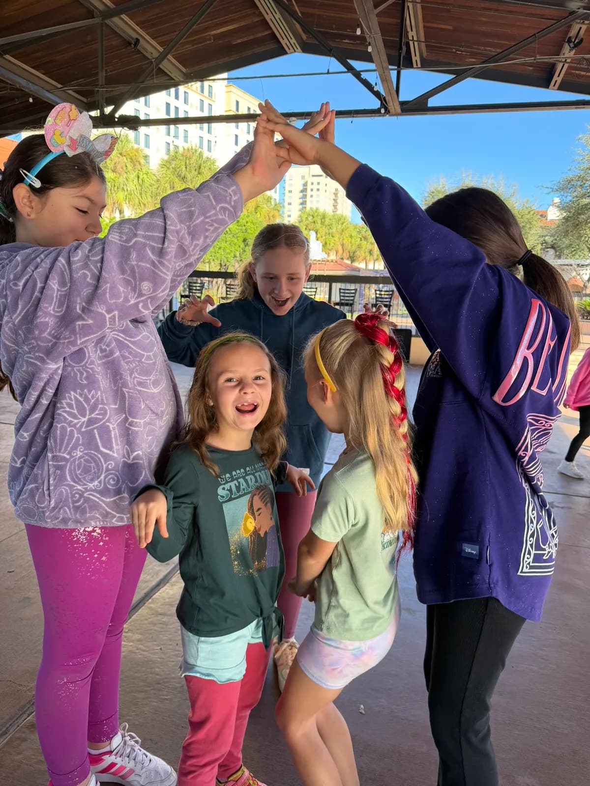 Campers forming an arch with their arms at an outdoor pavilion