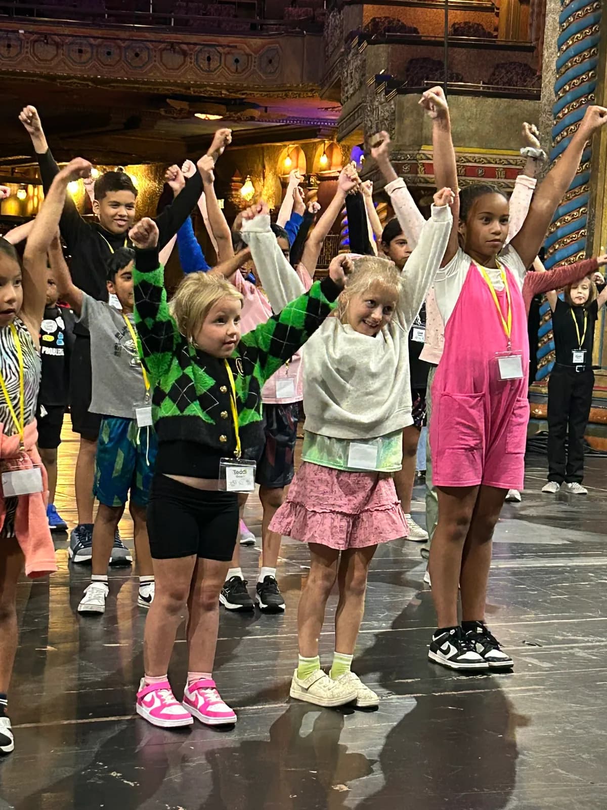 Campers dancing with fists raised on a Broadway-style stage