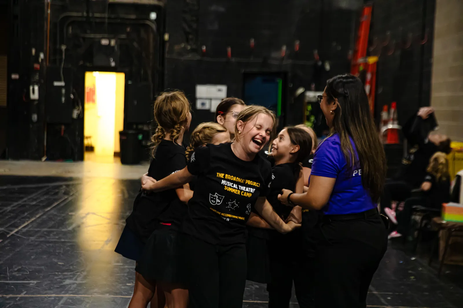 Campers sharing a group hug and laughing backstage