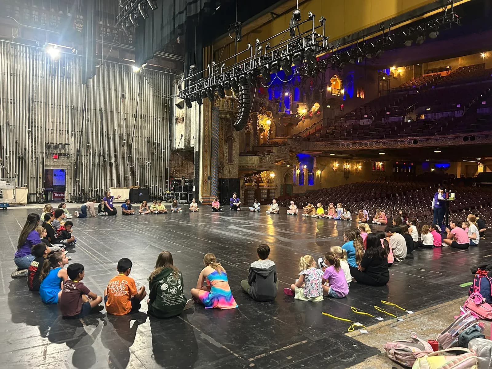 Wide shot of campers seated onstage in a historic theatre