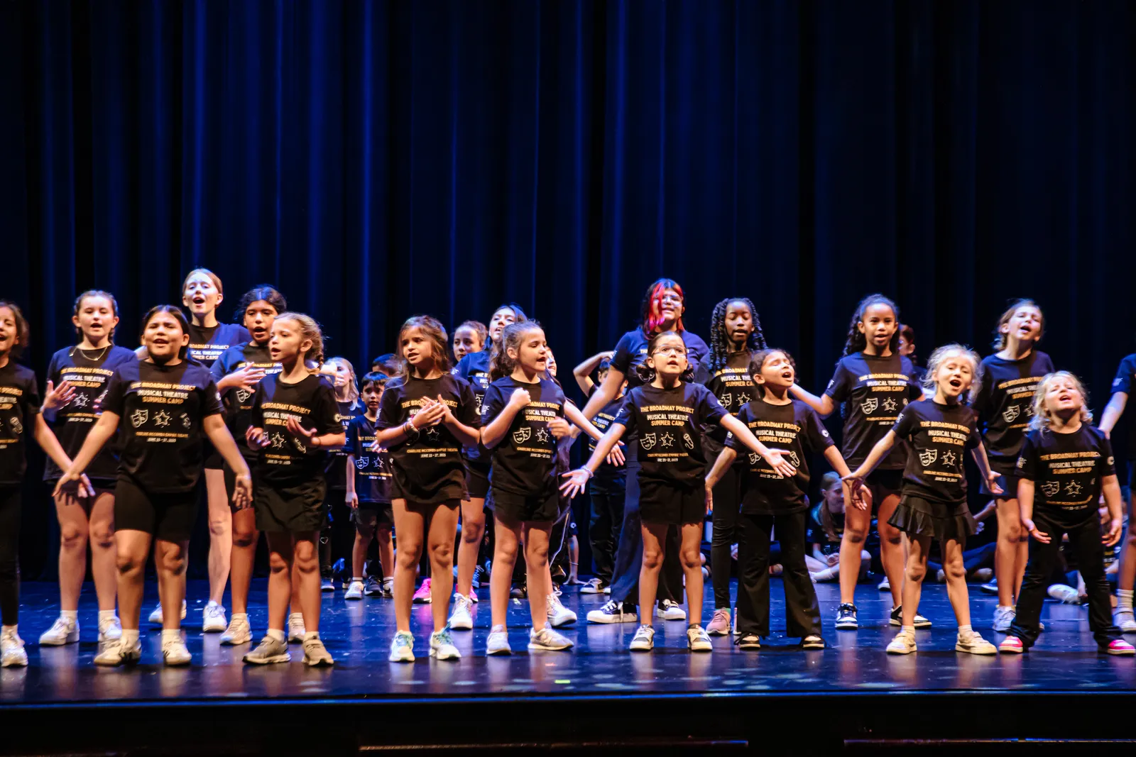 Close-up of campers singing onstage in camp T-shirts